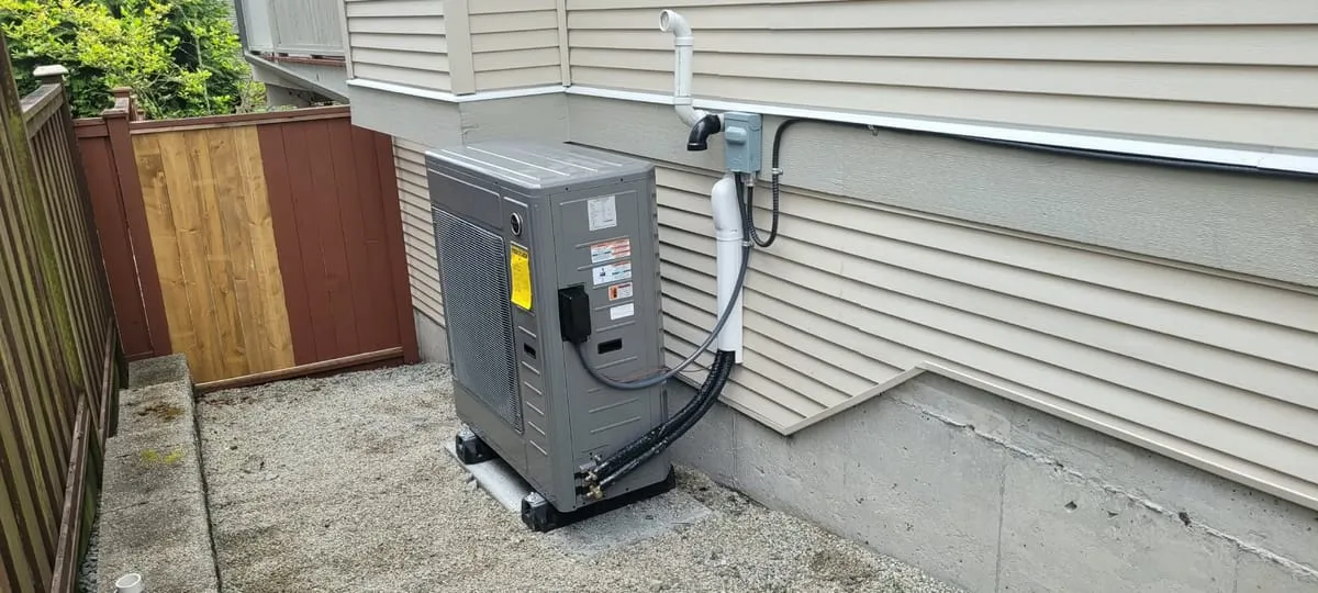 Heat pump outdoor unit on a pad beside a house